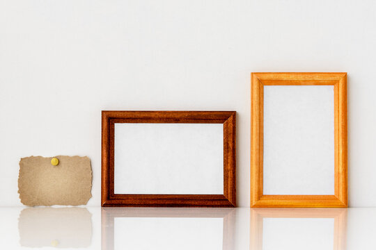 Two wooden frames with a white insert inside and a piece of kraft paper.
