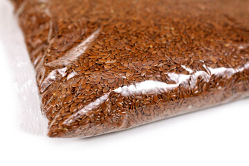Brown linen seeds in a transparent plastic bag isolated on a white background.