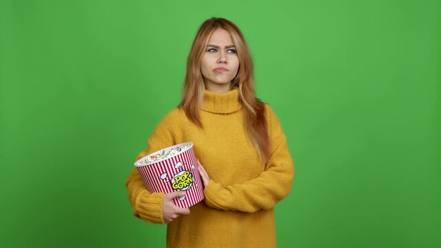 Teenager girl holding a bowl of popcorns having doubts and questioning an idea over isolated background