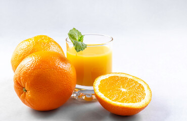 Natural 100% orange juice. Fresh oranges and orange juice in glasses on an gray background. Close up. Copy space.