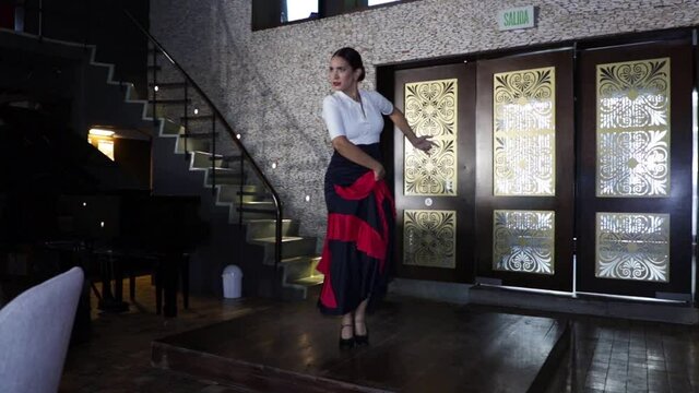 Spanish flamenco dancer dancing on a wooden stage inside a restaurant