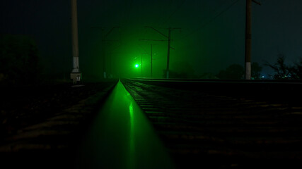 Empty railroad at night. Green traffic lights. A strong wind shakes the trees