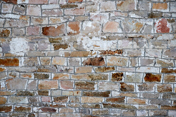 texture of an old stone wall with masonry seams and traces of stucco