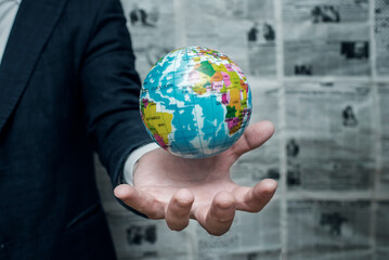 Earth planet in male hand on newspaper background. Businessman holding Earth