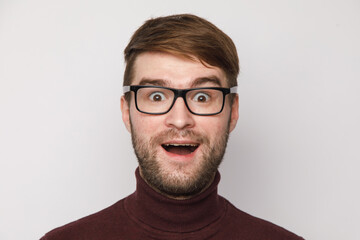 studio portrait of a guy on a light background, the surprise of a young man