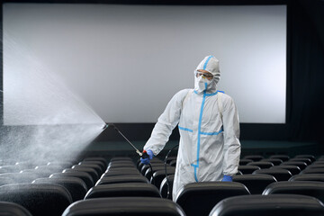 Worker holding equipment with disinfectants for chairs.