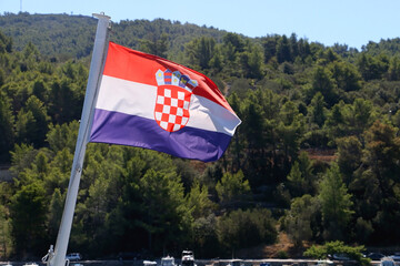 Flag of Croatia, blowing in the wind. Adriatic sea, island and boats in the background. Selective...