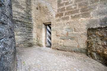 Old heavy shabby door built in a medieval stone wall