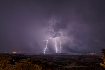 Naklejka na ściany i meble Beautiful night sky with lightning and thunderbolts during a thunderstorm in the countryside