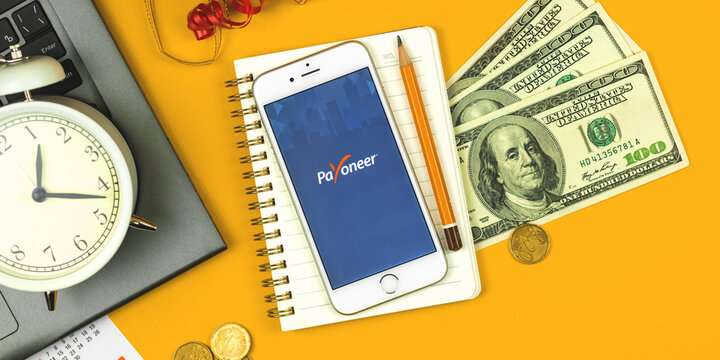 Kharkov, Ukraine - February 5, 2021: Payoneer application on Apple smartphone, online electronic finance payment sustem and service creative concept flat lay background