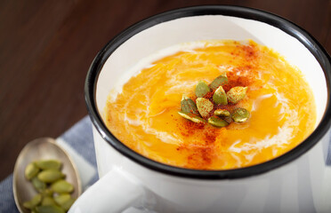 Thick Vegan Creamy Pumpkin Soup with Seeds and Paprika in a White Cup