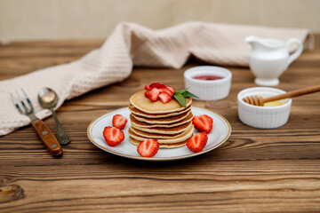 Healthy summer breakfast, homemade classic American pancakes with fresh berries and honey on a wooden background. Delicious pastries, dessert.