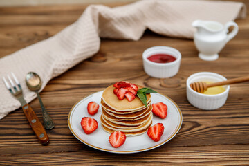 Healthy summer breakfast, homemade classic American pancakes with fresh berries and honey on a wooden background. Delicious pastries, dessert.