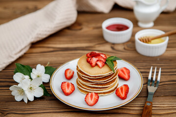 Healthy summer breakfast, homemade classic American pancakes with fresh berries and honey on a wooden background. Delicious pastries, dessert.