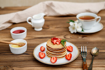 Healthy summer breakfast, homemade classic American pancakes with fresh berries and honey on a wooden background. Delicious pastries, dessert.