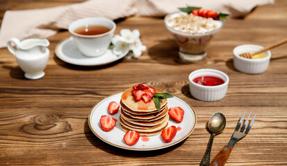 Healthy summer breakfast, homemade classic American pancakes with fresh berries and honey on a wooden background. Delicious pastries, dessert.