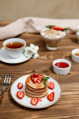 Fototapeta na wymiar Healthy summer breakfast, homemade classic American pancakes with fresh berries and honey on a wooden background. Delicious pastries, dessert.