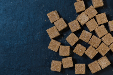 Cane sugar cubes, top view. Black background. Brown sugar texture