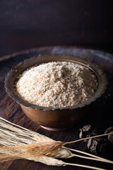Raw wheat germ in the metal bowl on wooden background. Wheat germ in bowl in front of a dark background. 