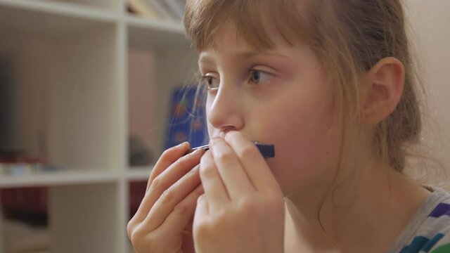Sad girl playing the harmonica closeup home interior