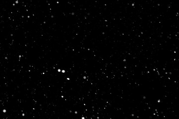 Naklejka na ściany i meble Bokeh of white snow on a black background. Falling snowflakes on night sky background, isolated for post production and overlay in graphic editor.
