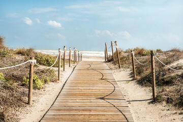 Fototapeta na wymiar Camino de aceso de madera a la playa rodeado de dunas en la costa del mar mediterraneo en una playa de Canet de Berenguer en Valencia, España. 