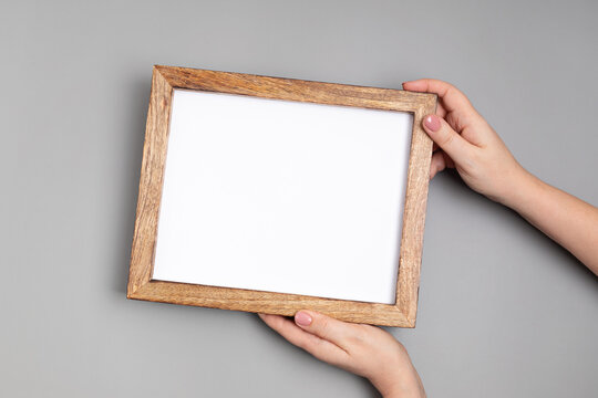 Woman hands holding blank wooden frame . Mockup, template