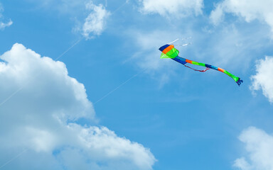 Colorful kite on cloudy blue sky background. Summer holidays concept. © besjunior