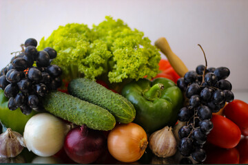 Prepare for a wonderful vegetarian lunch. Washed bell peppers, green cucumbers, onions, garlic, grapes and lettuce leaves
