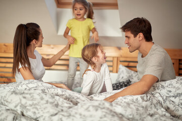 Mom and Dad enjoying with their kids in the bedroom. Family, home, together