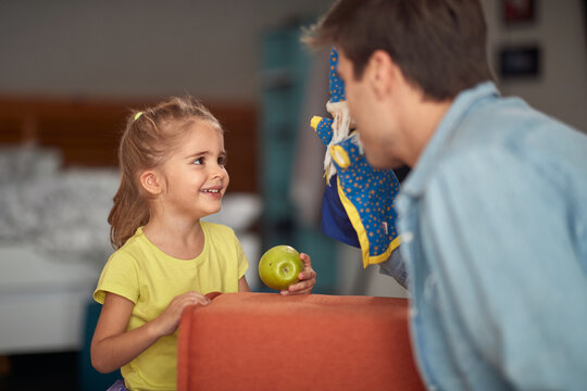 A little girl at home enjoying her father performance with a doll. Family, home, playing