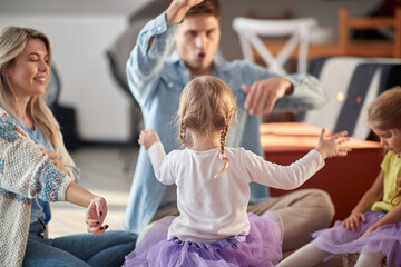 Young parents playing with their little daughters at home. Family, home, playing