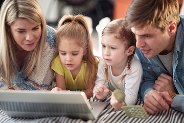 A young happy family watching laptop content together at home. Family, home, togethernes