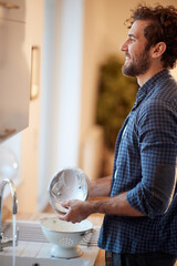 A cheerful young man enjoying housework in the kitchen. Kitchen, housework, quarantin, home