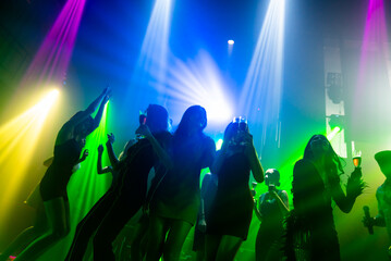Silhouette image of people dance in disco night club to music from DJ on stage . New year night...