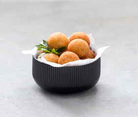 Vegan potato croquettes with parsley in a bowl on a light gray background