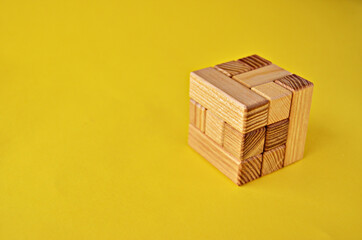 Logical game wooden cube puzzle in collected form close up on a yellow background with copy space. High quality photo