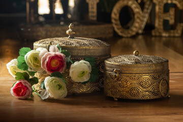 Decorative openwork boxes with a lid, artificial flowers. On a wooden table. Home accessories