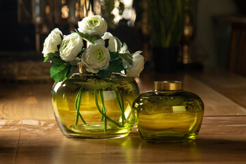 Beautiful glass vases, with flowers, green glass and gold edging, on a wooden table, household items, retro