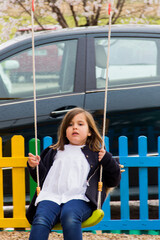 quiet little girl on outdoor playground swing