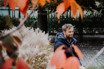 Artistic photo portrait confident smiling handsome middle-aged Caucasian man portraited in the city, with white skin, grey and black hair having a friendly look on his face, wearing a blue jacket.