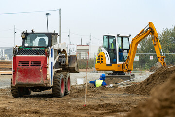 Two small excavators digging a trench on a construction site.