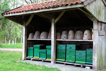 Reconstructed old fashioned bee barn for beekeeping. There are two rows of beehives in. Baskets and boxes. Bee skeps.