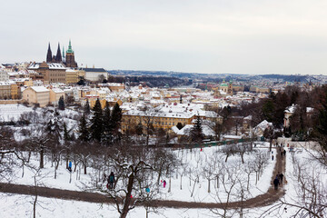 Obraz premium Snowy Prague City with gothic Castle from Hill Petrin in the sunny Day, Czech republic