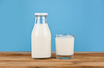 Glass and bottle of milk over blue