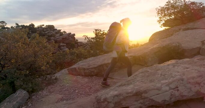 Mujer adulta escalando con mochila cima al amanecer dorado