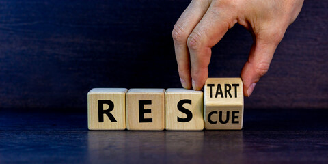 Rescue and restart symbol. Businessman hand turns cubes and changes the word 'rescue' to 'restart'....