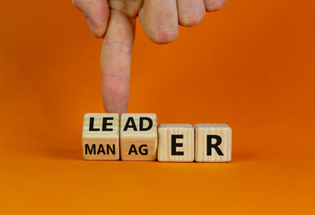 Manager versus leader symbol. Businessman flips wooden cubes and changes the word 'manager' to...