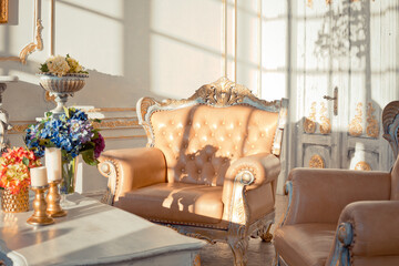 rich apartment interior with golden baroque decorations on the walls and luxury furniture. the room is flooded with the rays of the setting sun