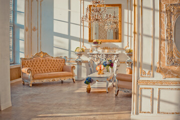 rich apartment interior with golden baroque decorations on the walls and luxury furniture. the room is flooded with the rays of the setting sun